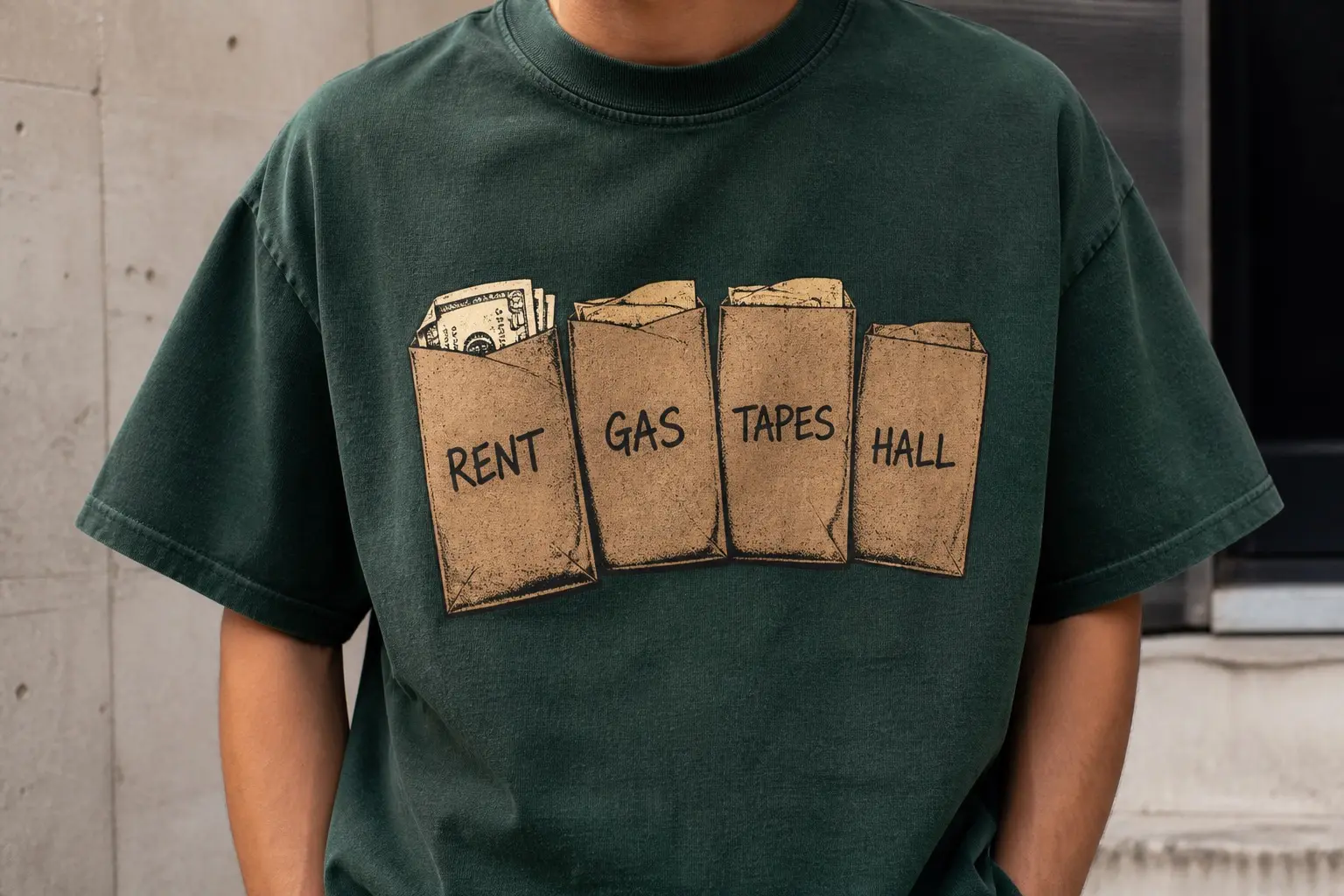 A forest green tee printed with four small brown envelopes laid in an overlapping row, each bulging slightly and carrying one marker word — RENT, GAS, TAPES, HALL — with the fourth, HALL, visibly the flattest of the four, and no other text