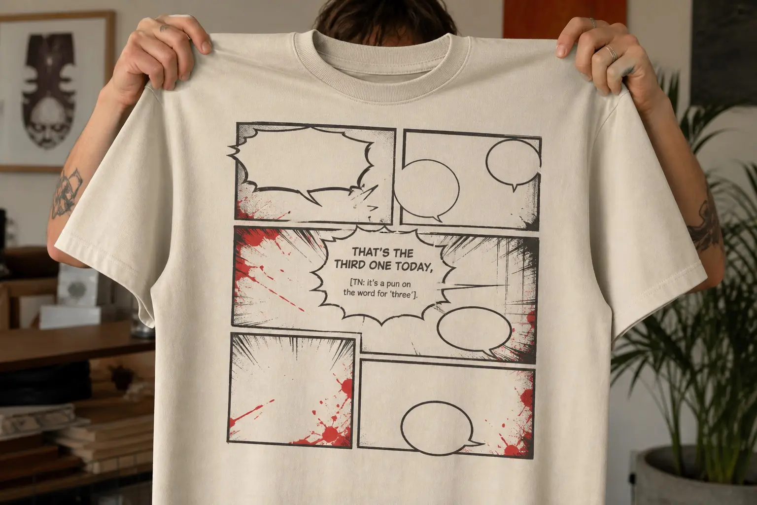 A comic page held up in two hands, panel borders drawn as empty rectangles with no artwork inside, one balloon reading THAT'S THE THIRD ONE TODAY above a smaller bracketed line reading TN it's a pun on the word for three