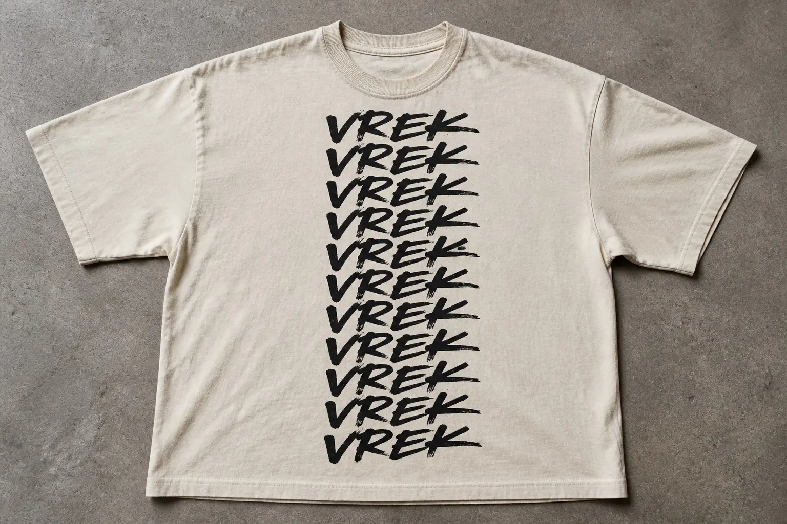 A bone tee laid flat overhead, printed with the invented tag VREK written eleven times down the chest in a fast, confident marker hand, the same slant and the same loop on the R and the same trailing flick off the K repeating with only the small variation of a practised signature.