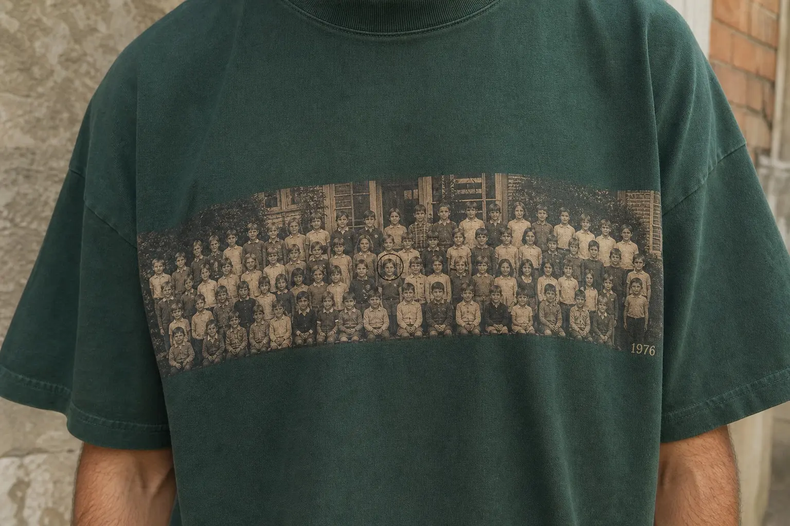 A deep green t-shirt worn from the chest down, the wide strip spanning the full chest, printed with an extremely wide, short panoramic school photograph of five rows of children standing outside a building, sepia toned, with a small year printed at the right-hand end