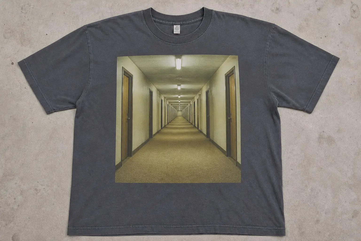 A slate tee printed with a photographic image of an empty yellow-carpeted hotel corridor receding to a vanishing point, printed as a hard-edged rectangle